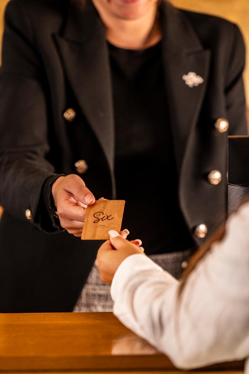 une personne tenant un morceau de papier entre ses mains dans l'établissement Hotel Le Six, à Paris