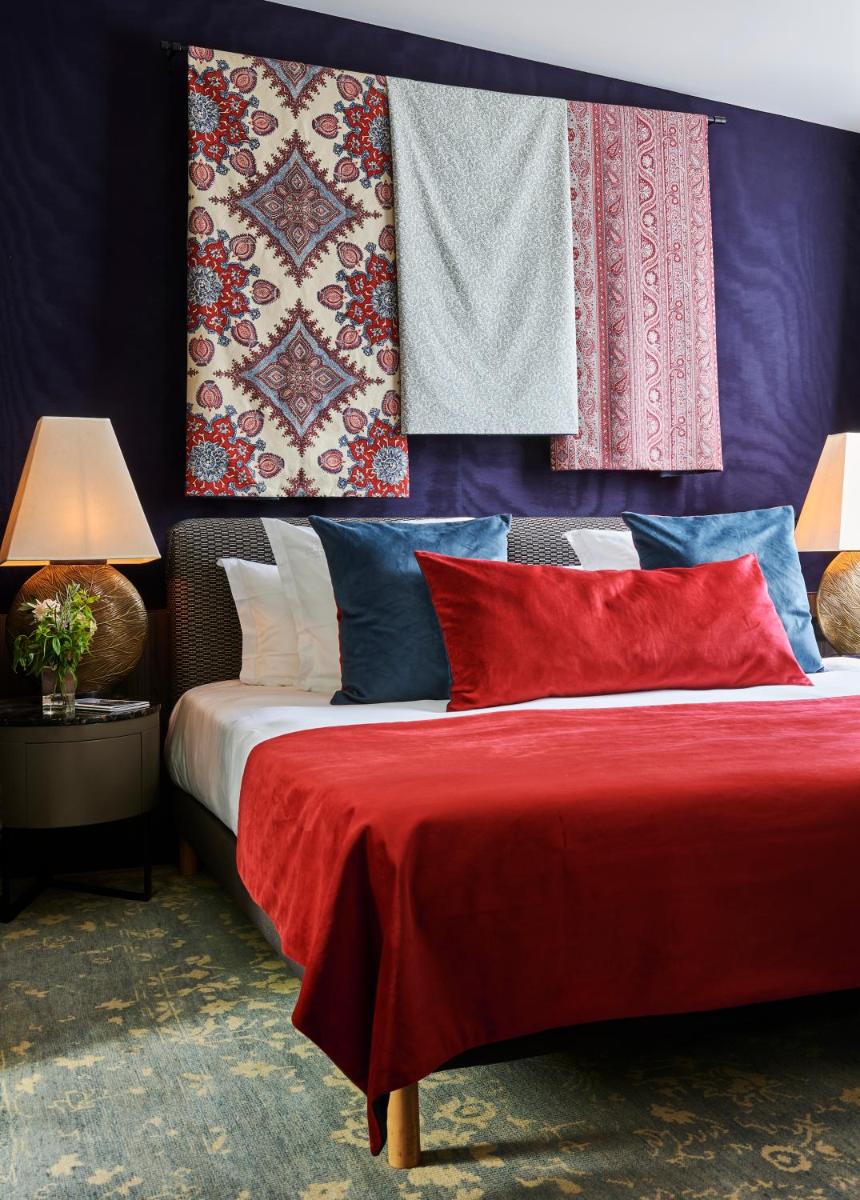 - une chambre avec un lit doté d'oreillers et de couvertures colorés dans l'établissement Maison Boissière BARNES Residences, à Paris