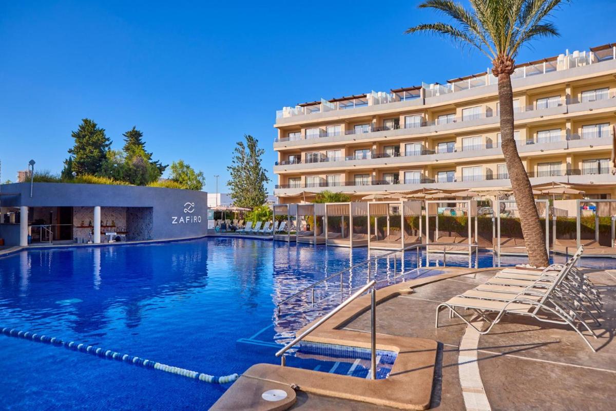 un hotel con una piscina con sillas y una palmera en Zafiro Palmanova, en Palmanova