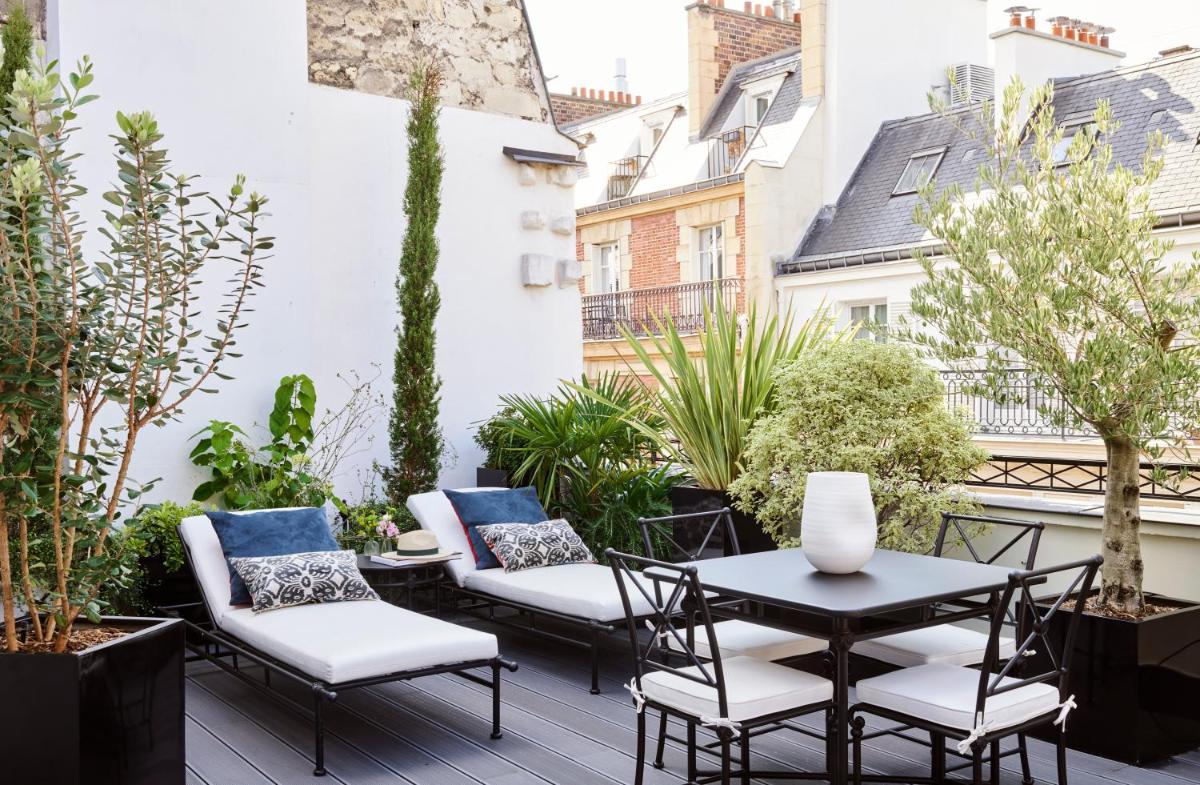 un patio avec une table, des chaises et des plantes dans l'établissement Maison Boissière BARNES Residences, à Paris