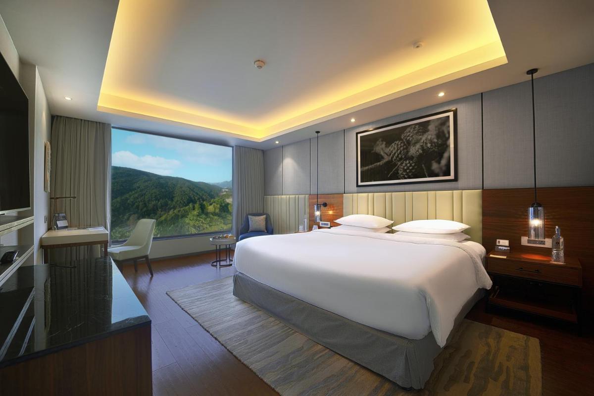 a bedroom with a large bed and a large window at Hyatt Regency Dehradun Resort and Spa in Dehradun