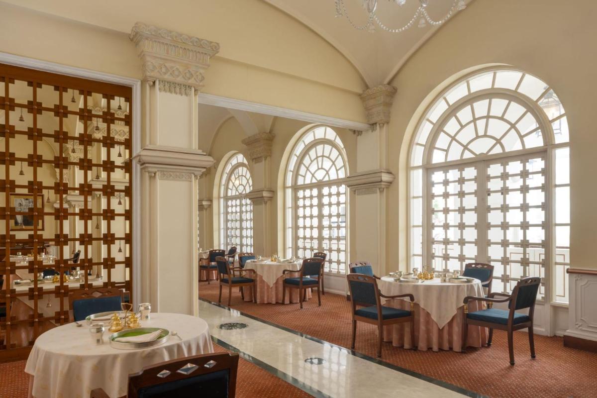 a dining room with tables and chairs and large windows at ITC Windsor, a Luxury Collection Hotel, Bengaluru in Bengaluru a dining room with tables and chairs and large windows at ITC Windsor, a Luxury Collection Hotel, Bengaluru in Bengaluru