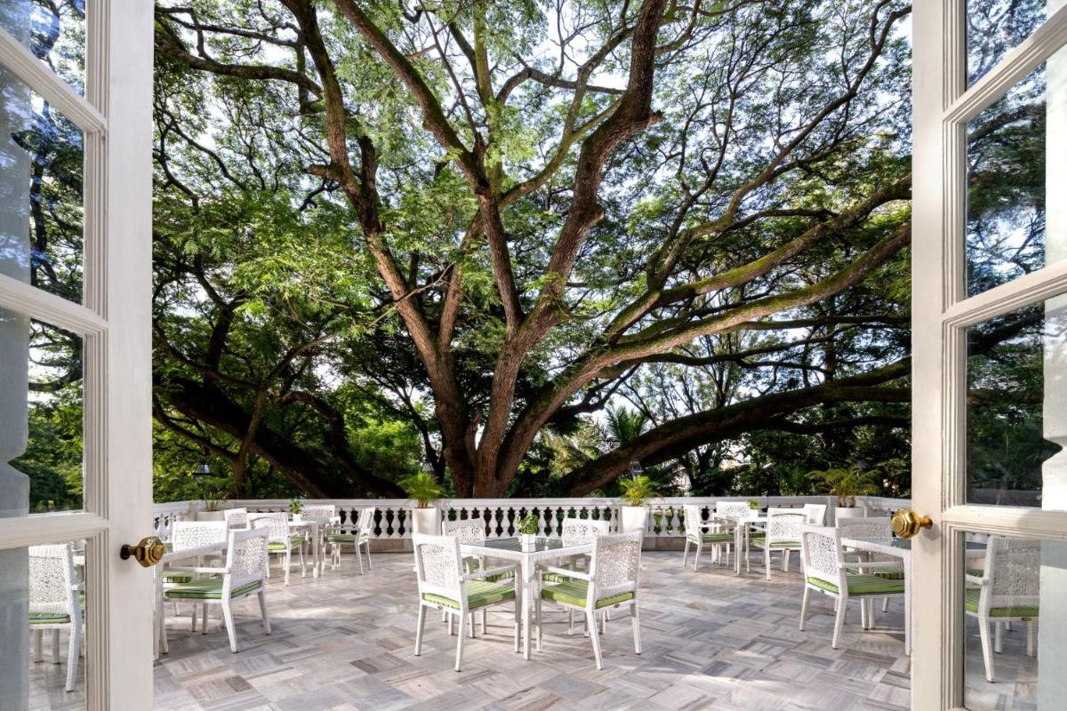 a group of tables and chairs in front of a tree at ITC Windsor, a Luxury Collection Hotel, Bengaluru in Bengaluru a group of tables and chairs in front of a tree at ITC Windsor, a Luxury Collection Hotel, Bengaluru in Bengaluru