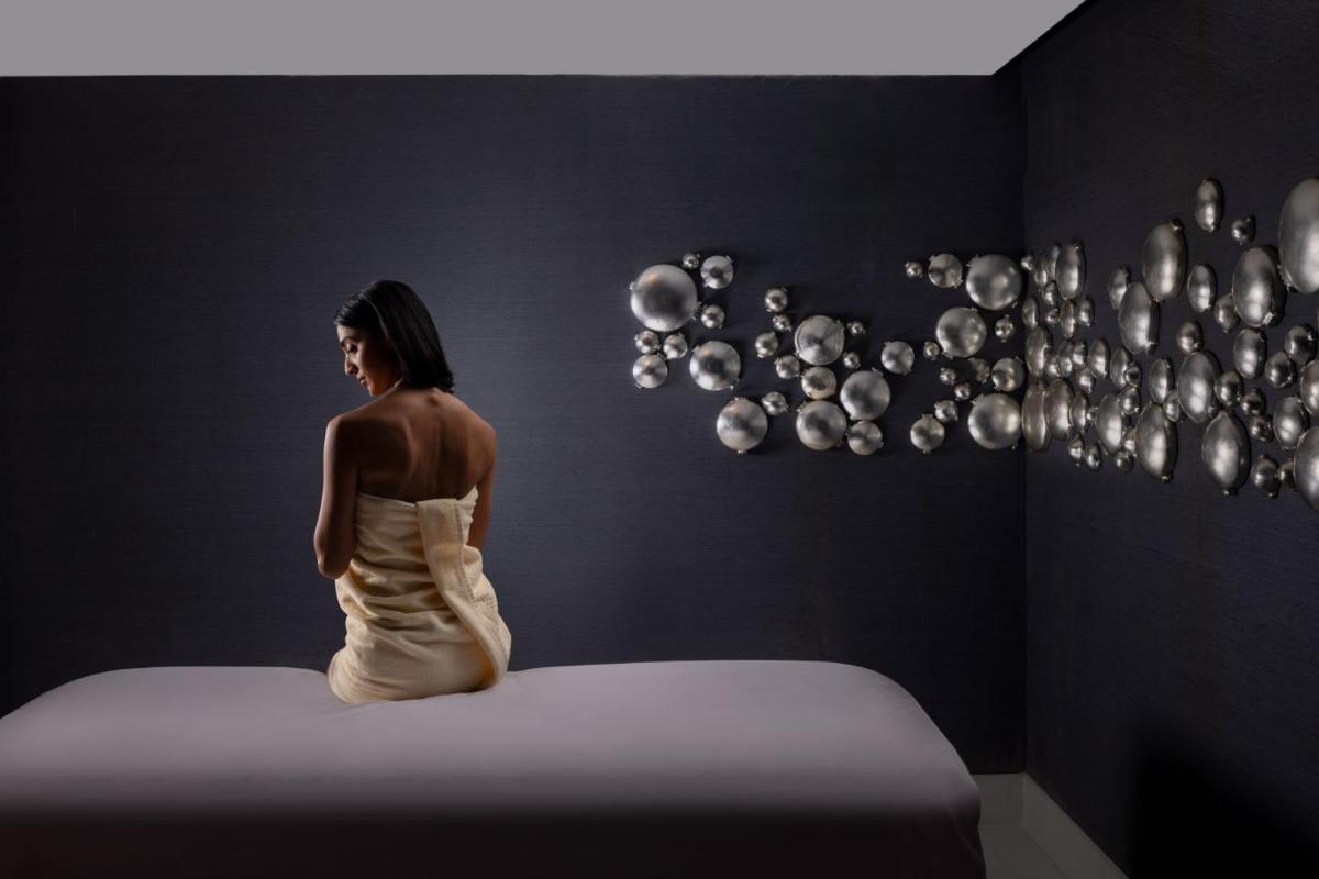 a woman sitting on a bed in a room with bubbles at ITC Windsor, a Luxury Collection Hotel, Bengaluru in Bengaluru a woman sitting on a bed in a room with bubbles at ITC Windsor, a Luxury Collection Hotel, Bengaluru in Bengaluru