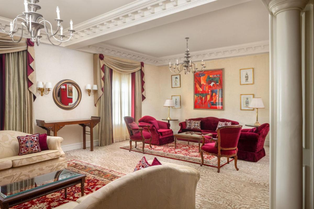 a living room with red chairs and a piano at ITC Windsor, a Luxury Collection Hotel, Bengaluru in Bengaluru a living room with red chairs and a piano at ITC Windsor, a Luxury Collection Hotel, Bengaluru in Bengaluru