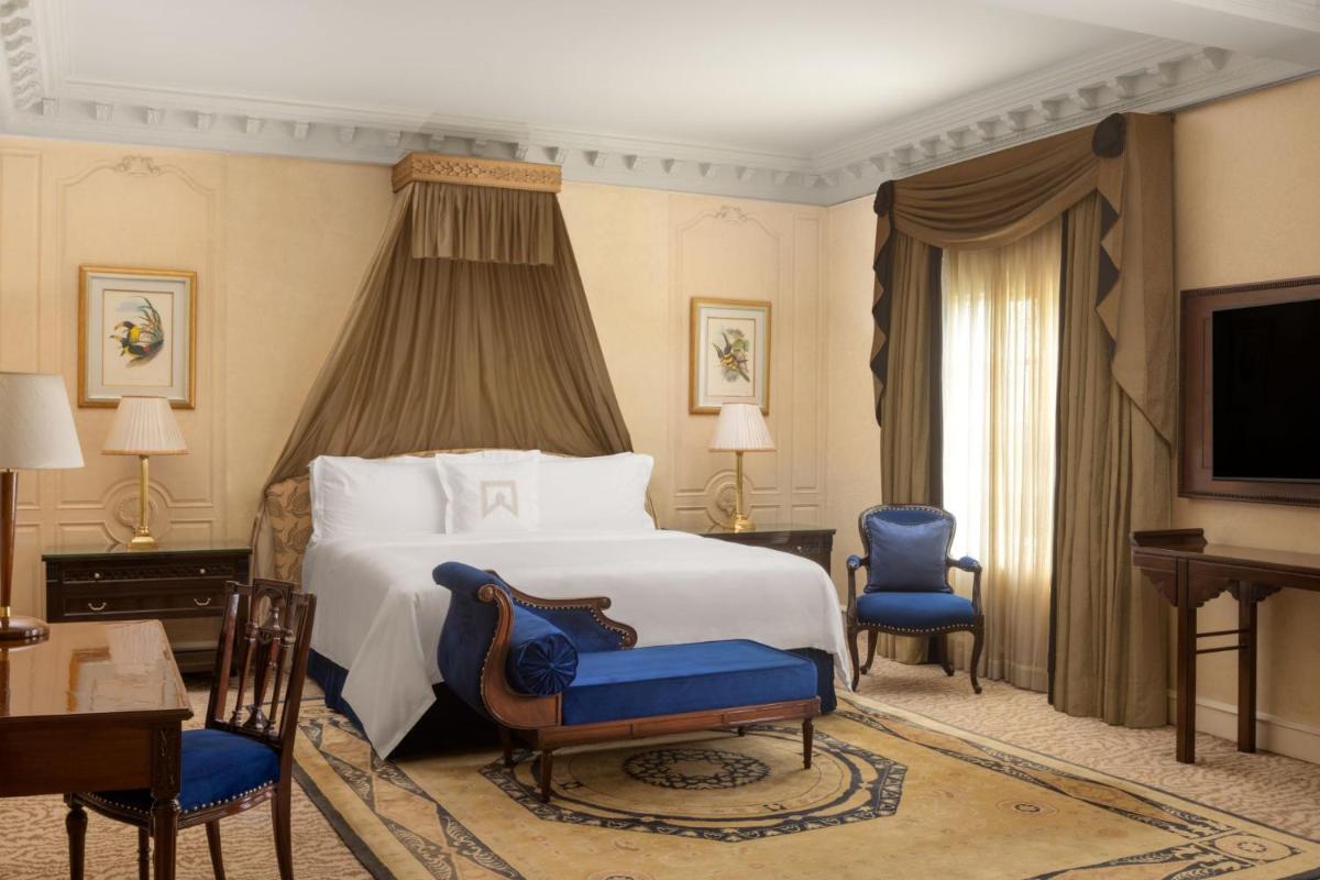 a bedroom with a large bed and blue chairs at ITC Windsor, a Luxury Collection Hotel, Bengaluru in Bengaluru a bedroom with a large bed and blue chairs at ITC Windsor, a Luxury Collection Hotel, Bengaluru in Bengaluru