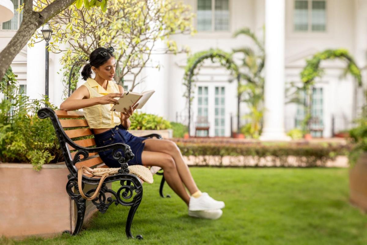 a woman sitting on a bench looking at a tablet at ITC Windsor, a Luxury Collection Hotel, Bengaluru in Bengaluru a woman sitting on a bench looking at a tablet at ITC Windsor, a Luxury Collection Hotel, Bengaluru in Bengaluru