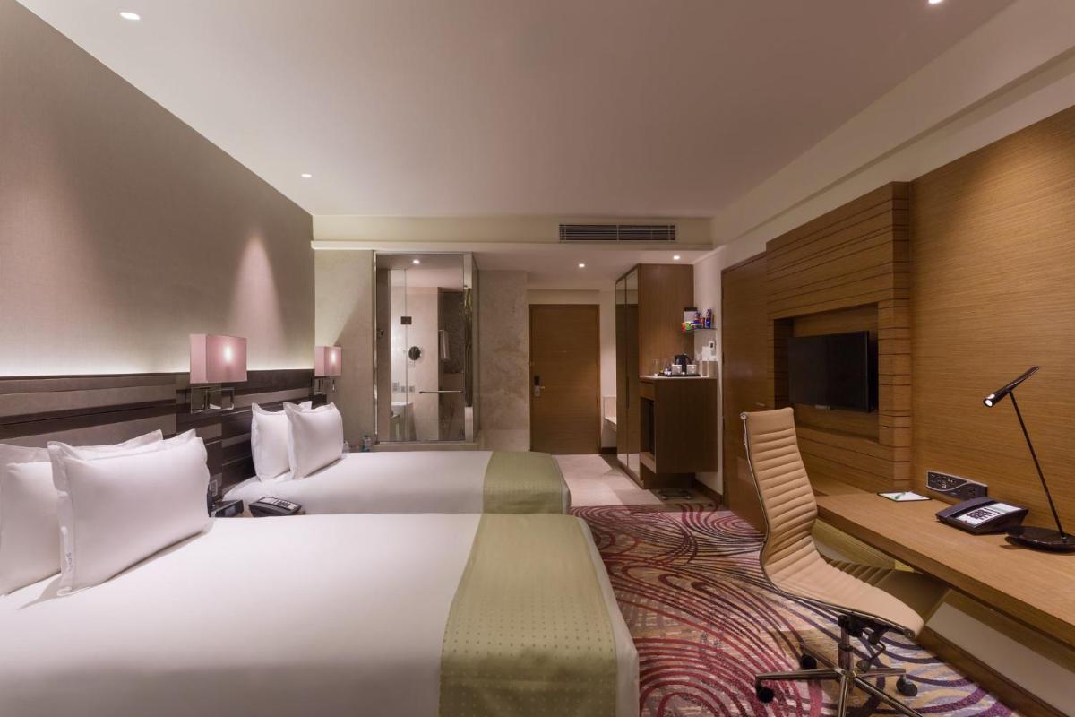 a hotel room with a large bed and a desk at Holiday Inn Jaipur City Centre by IHG in Jaipur a hotel room with a large bed and a desk at Holiday Inn Jaipur City Centre by IHG in Jaipur