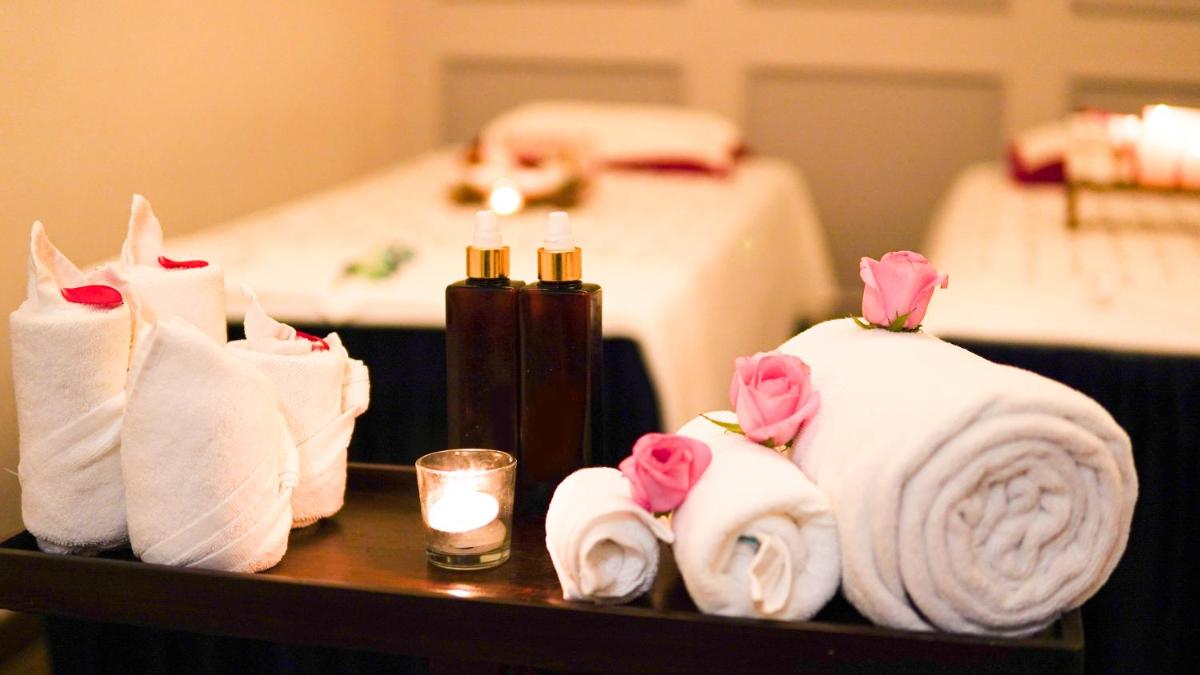 a table with towels and candles and a bed at Saraca Hotel Lucknow in Lucknow