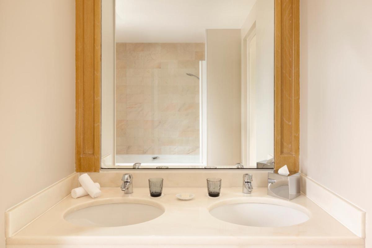 une salle de bain avec deux lavabos et un grand miroir dans l'établissement Le Castel Marie Louise, à La Baule 32 autres photos