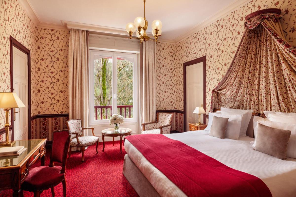une chambre d'hôtel avec un grand lit et un bureau dans l'établissement Le Castel Marie Louise, à La Baule une chambre d'hôtel avec un grand lit et un bureau dans l'établissement Le Castel Marie Louise, à La Baule
