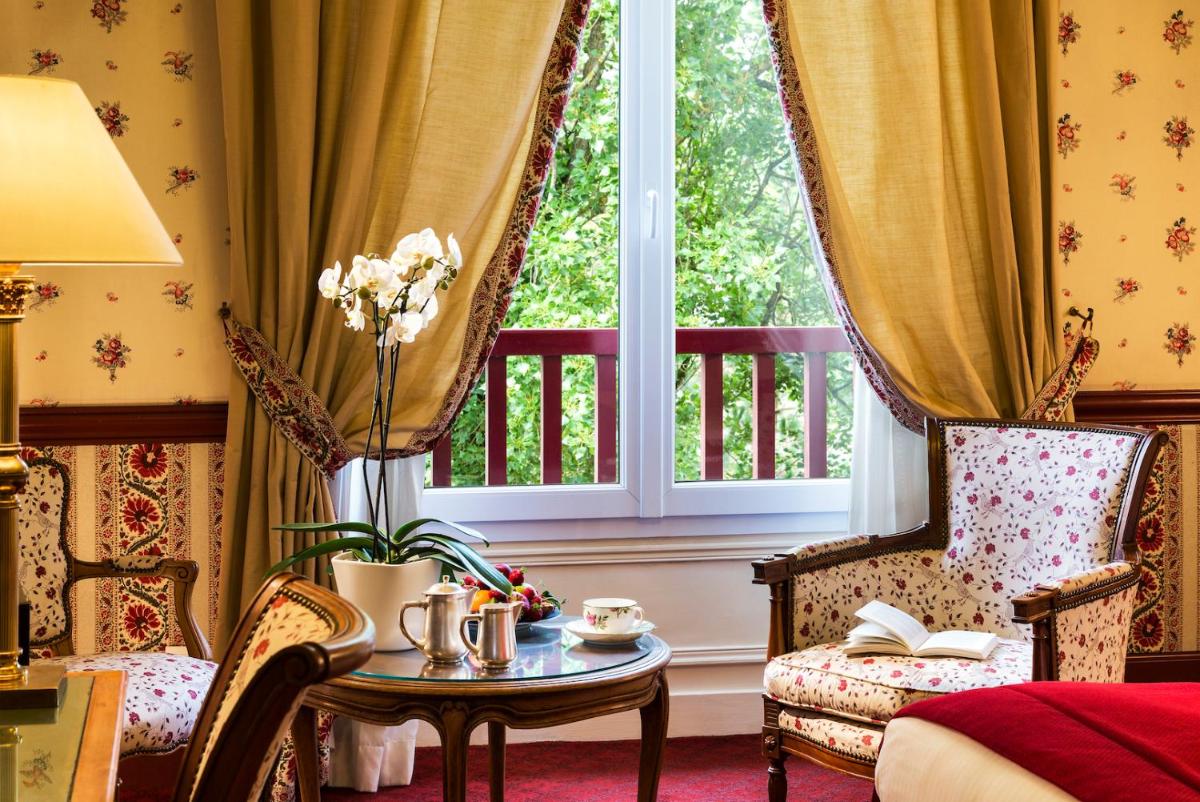 une pièce avec une table, des chaises et une fenêtre dans l'établissement Le Castel Marie Louise, à La Baule une pièce avec une table, des chaises et une fenêtre dans l'établissement Le Castel Marie Louise, à La Baule