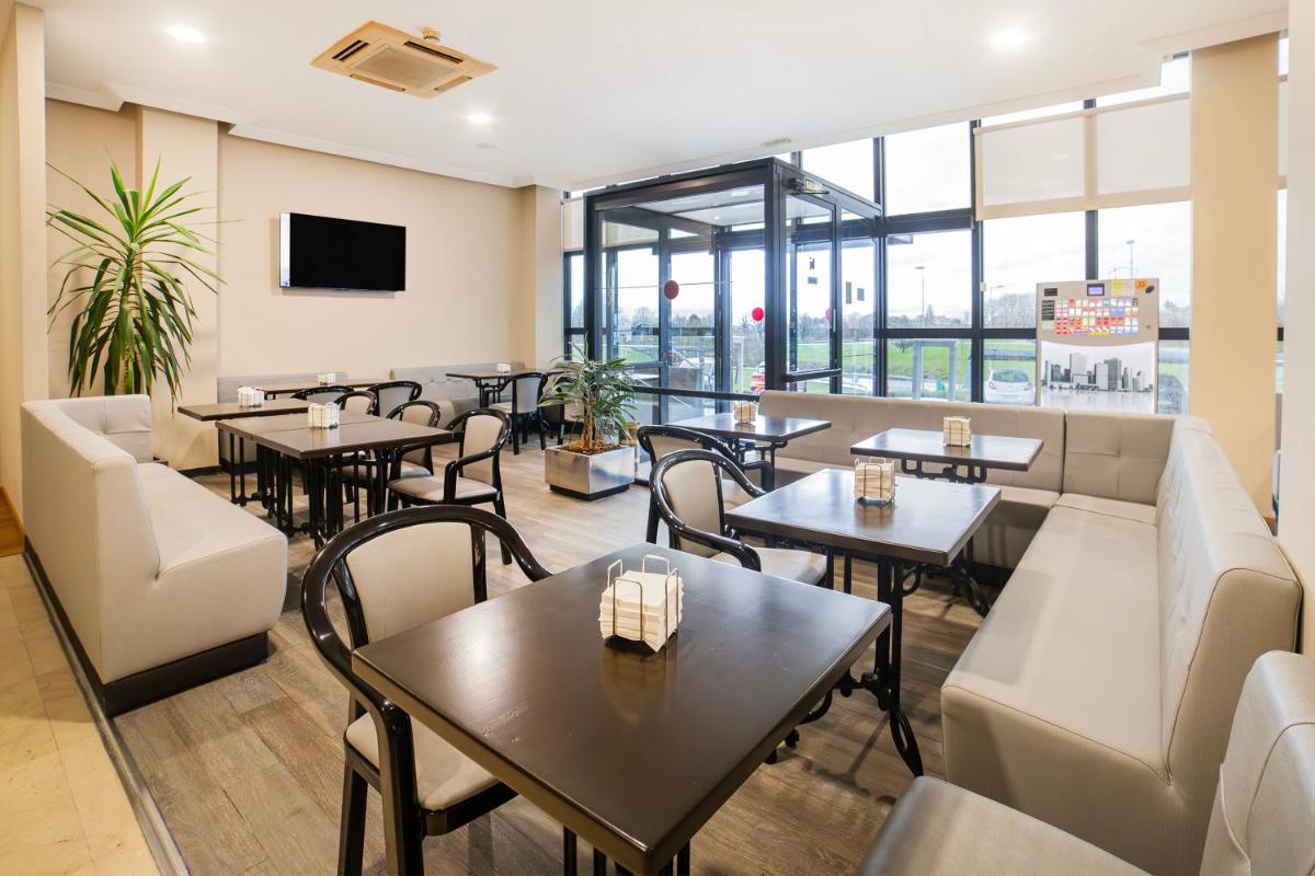 Un restaurante con mesas y sillas y un sofá. en Hotel Auditorio Santiago & Spa, en Lugo