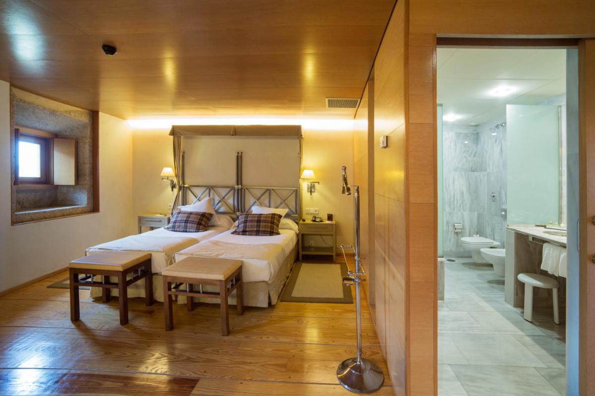Un dormitorio con una cama grande y un baño. en Parador de Santo Estevo, en Santo Estevo de Rivas de Sil