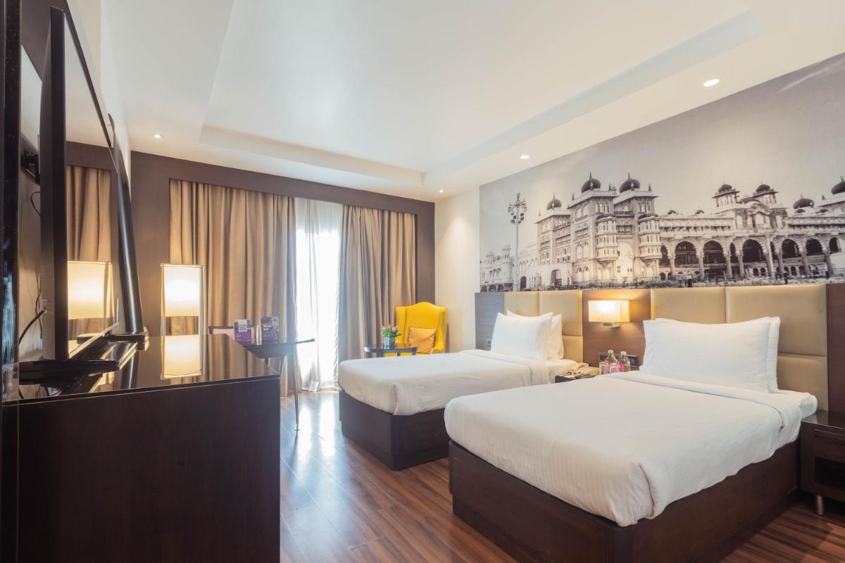 a hotel room with two beds and a television at Hotel Royal Orchid Bangalore in Bengaluru