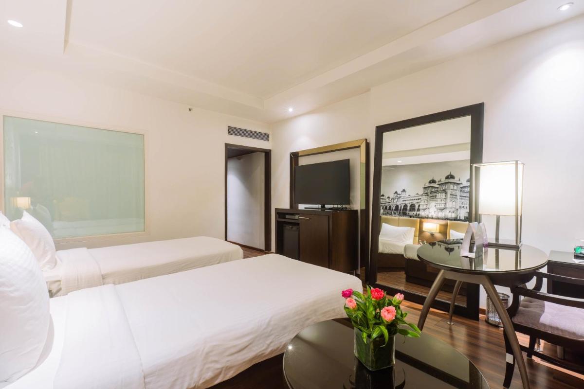 a hotel room with two beds and a table at Hotel Royal Orchid Bangalore in Bengaluru