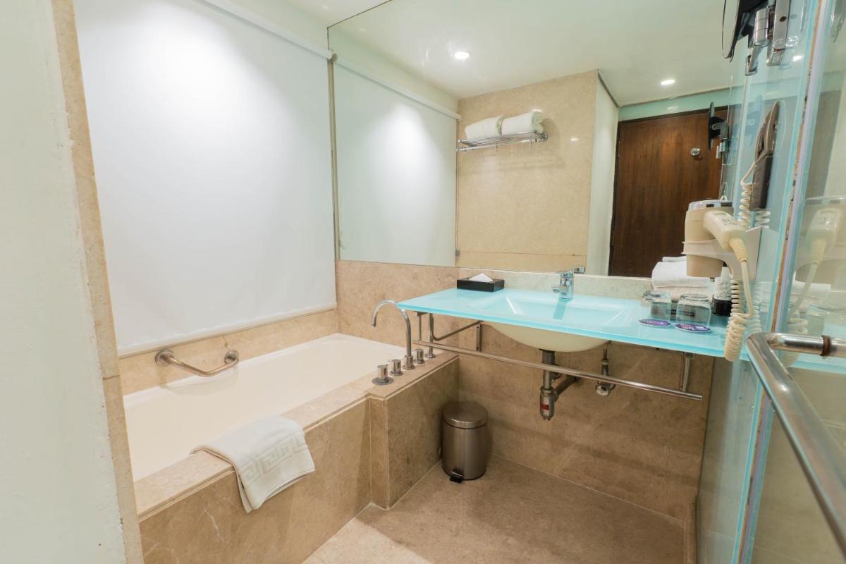 a bathroom with a bath tub and a sink at Hotel Royal Orchid Bangalore in Bengaluru