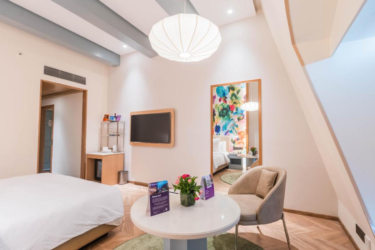 a bedroom with a bed and a table and a chair at Hotel Royal Orchid Bangalore in Bengaluru