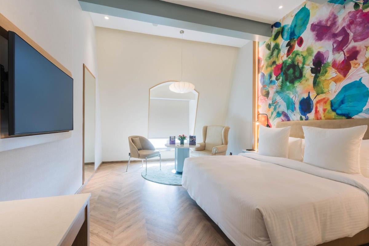a bedroom with a large bed and a painting on the wall at Hotel Royal Orchid Bangalore in Bengaluru