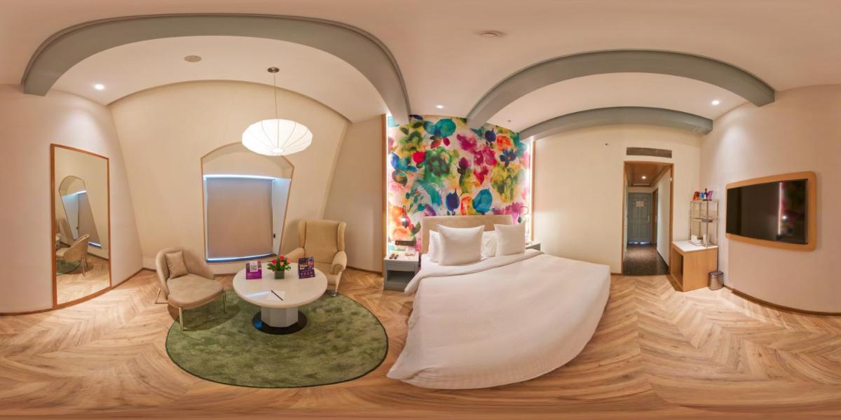 a hotel room with a large bed and a painting at Hotel Royal Orchid Bangalore in Bengaluru