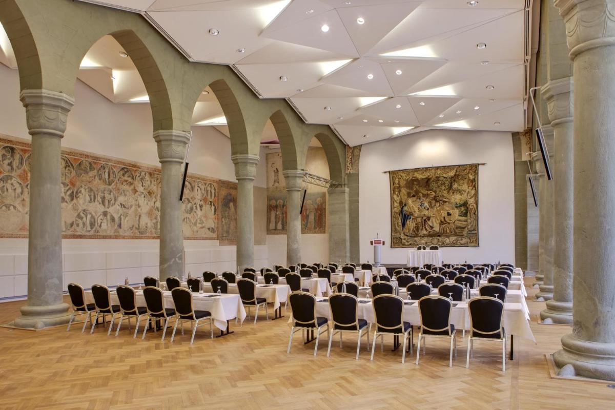 ein großer Saal mit Tischen und Stühlen in der Unterkunft Steigenberger Inselhotel in Konstanz