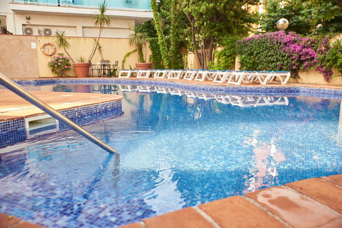 una piscina con sillas en un edificio en DWO Les Palmeres, en Calella
