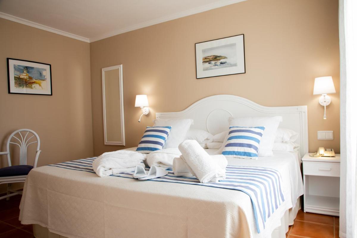 Un dormitorio con una cama blanca con almohadas azules y blancas. en DWO Les Palmeres, en Calella