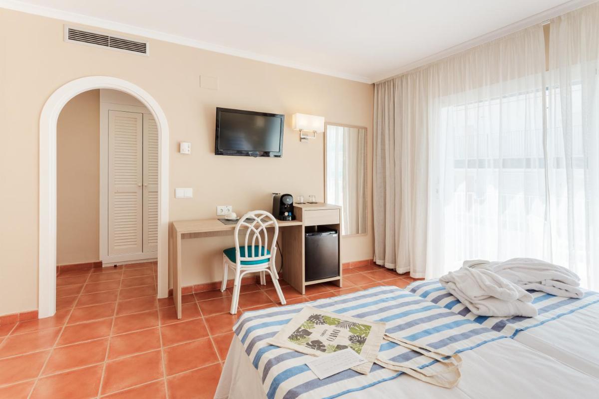 Un dormitorio con una cama, un escritorio y un televisor. en DWO Les Palmeres, en Calella