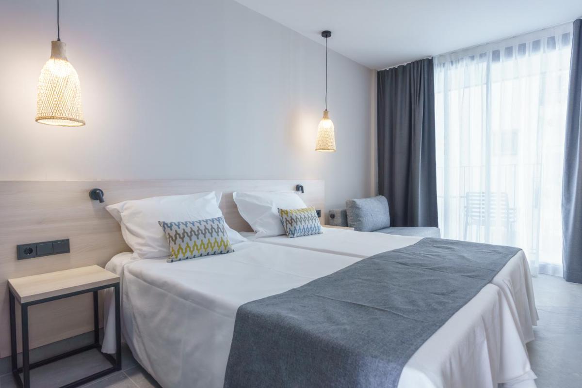 Un dormitorio con una gran cama blanca y una silla. en DWO Les Palmeres, en Calella