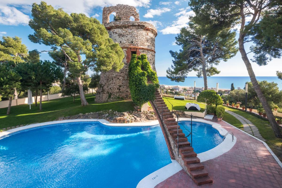 Una piscina al aire libre con una torre junto a un complejo turístico. en Gran Hotel Rey Don Jaime, en Castelldefels