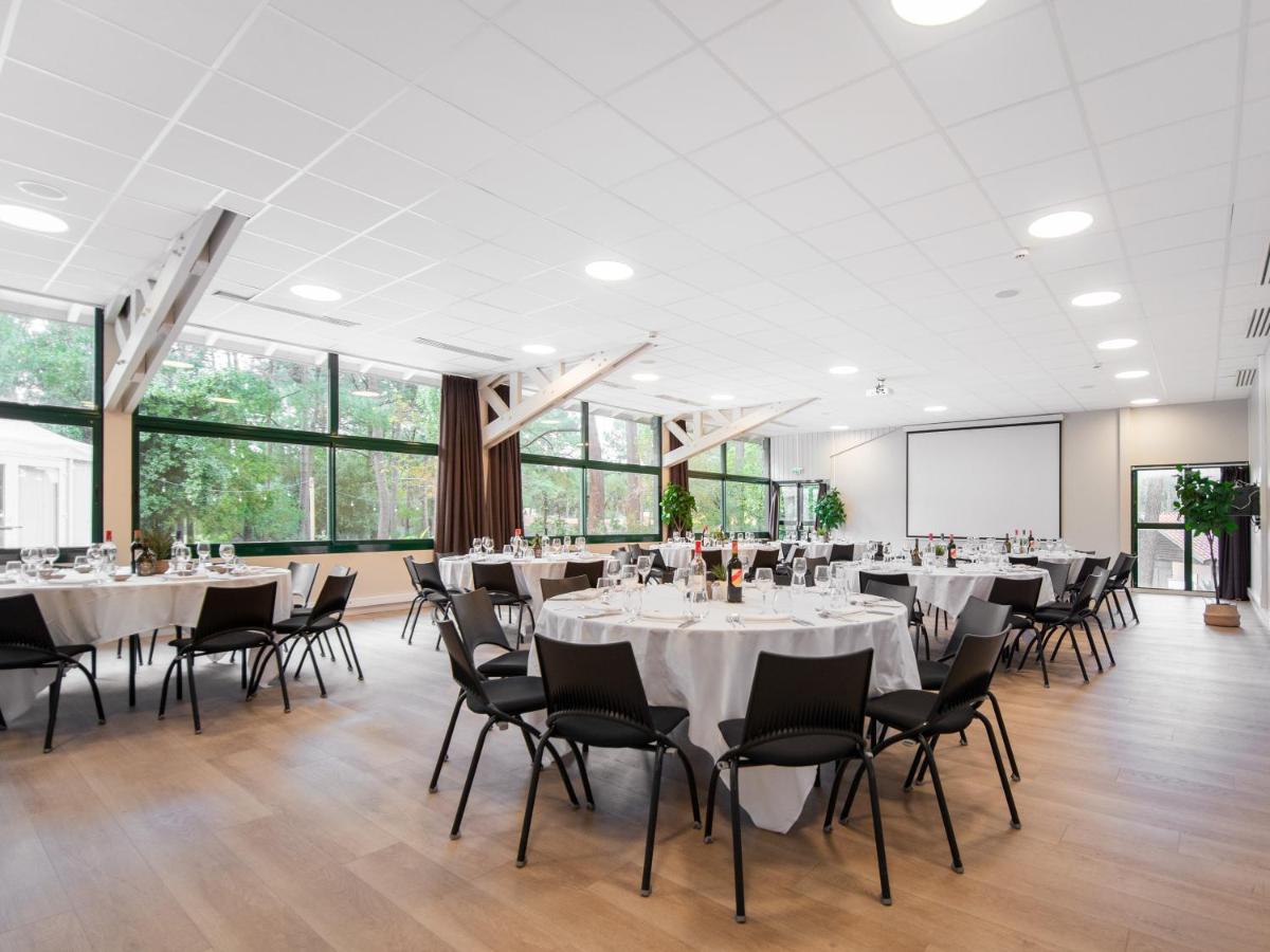 une salle de conférence avec des tables, des chaises et des fenêtres dans l'établissement Hôtel & Spa Vitalparc, The Originals Collection, à Lacanau-Océan
