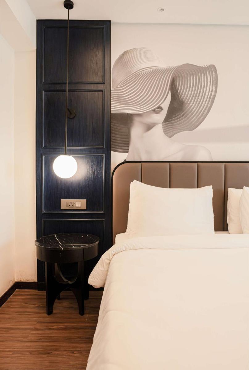 a bedroom with two beds and a picture of a woman at Radisson Blu Hotel Ahmedabad in Ahmedabad