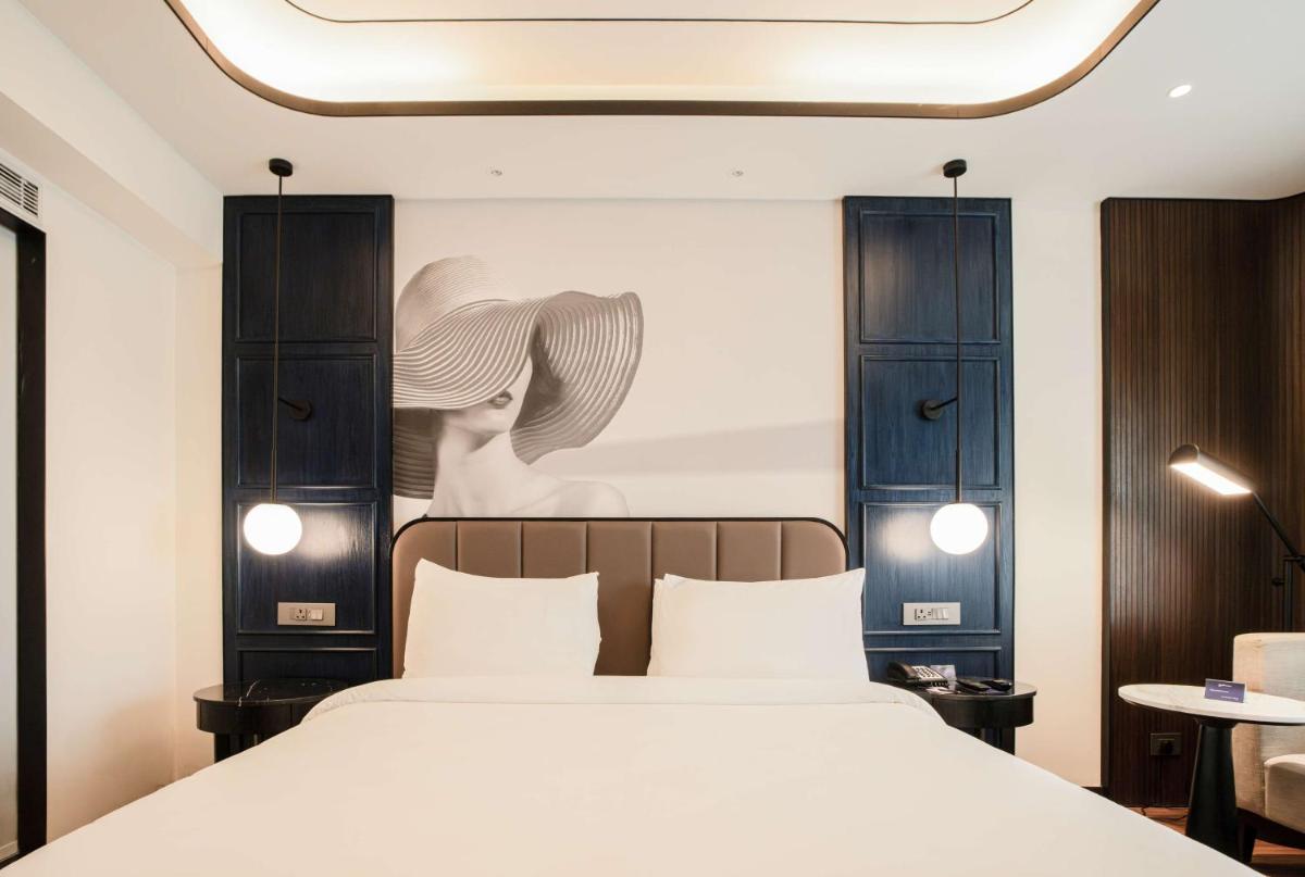 a bedroom with a bed and a painting of a woman at Radisson Blu Hotel Ahmedabad in Ahmedabad