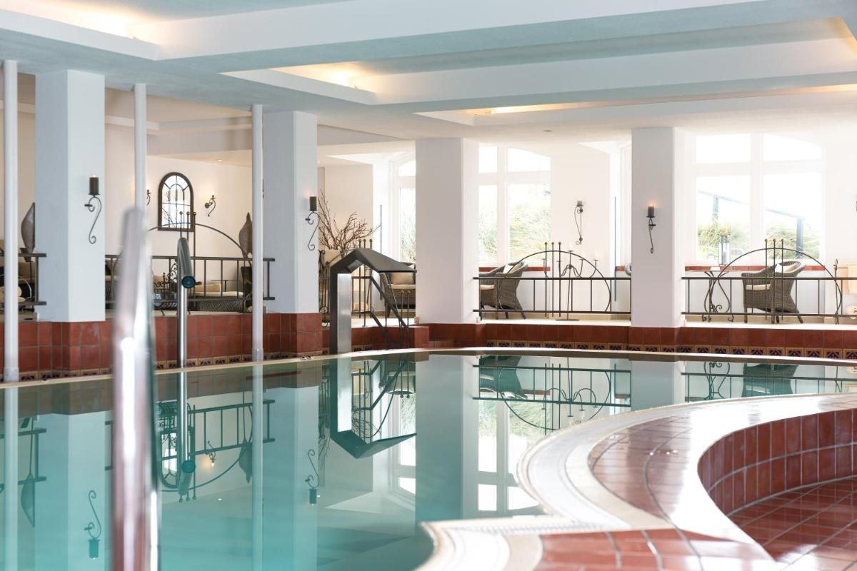 ein Swimmingpool mit Tischen und Stühlen in einem Gebäude in der Unterkunft Hotel Miramar in Westerland ein Swimmingpool mit Tischen und Stühlen in einem Gebäude in der Unterkunft Hotel Miramar in Westerland