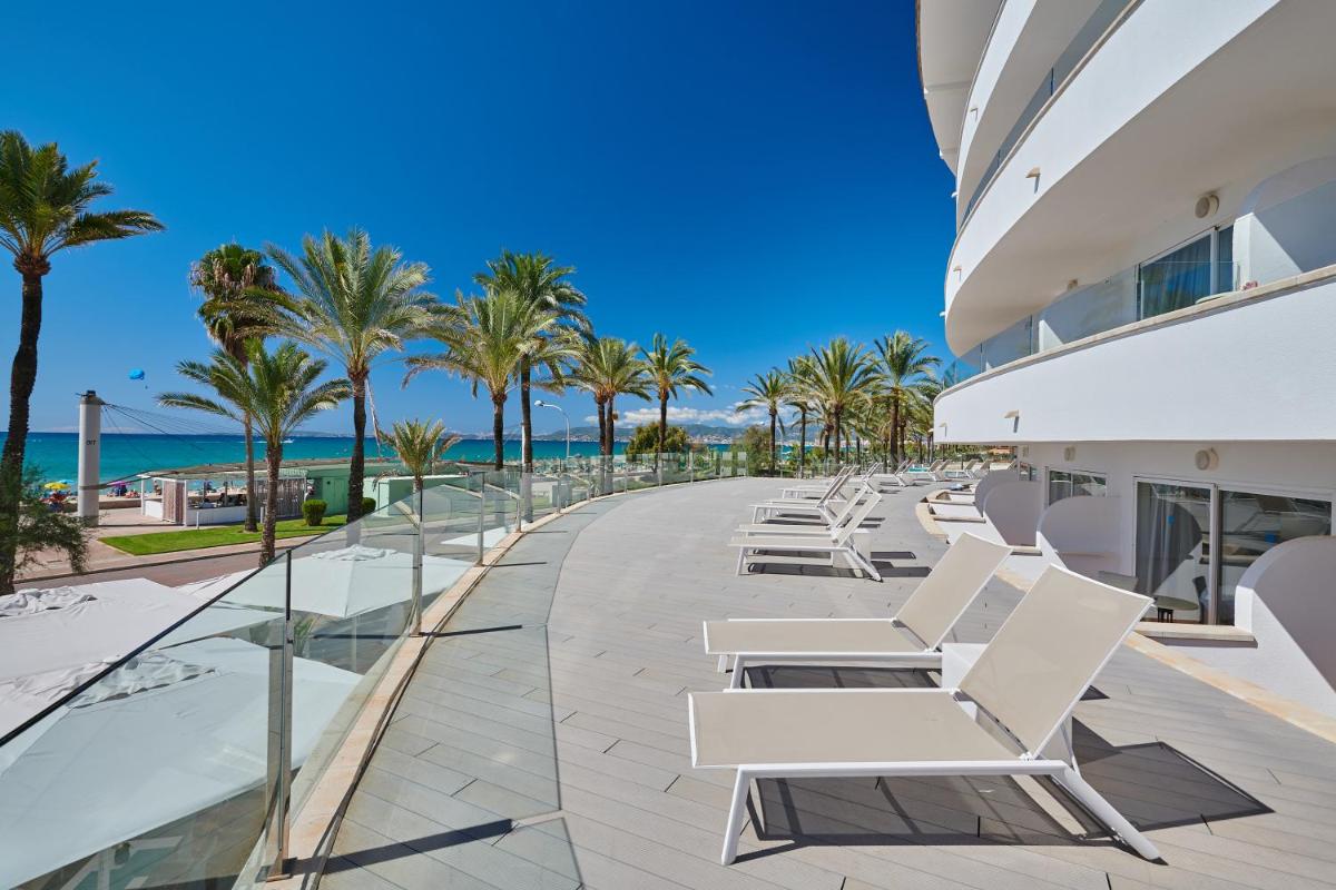 una fila de sillas blancas y palmeras en un edificio en Grupotel Acapulco Playa - Adults Only, en Playa de Palma