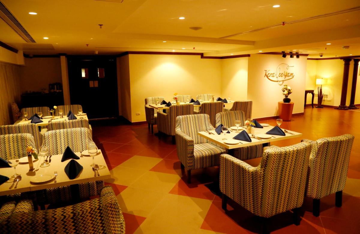 a restaurant with tables and chairs in a room at The Raviz Calicut in Kozhikode