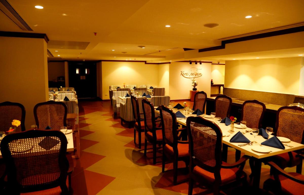 a restaurant with tables and chairs in a room at The Raviz Calicut in Kozhikode