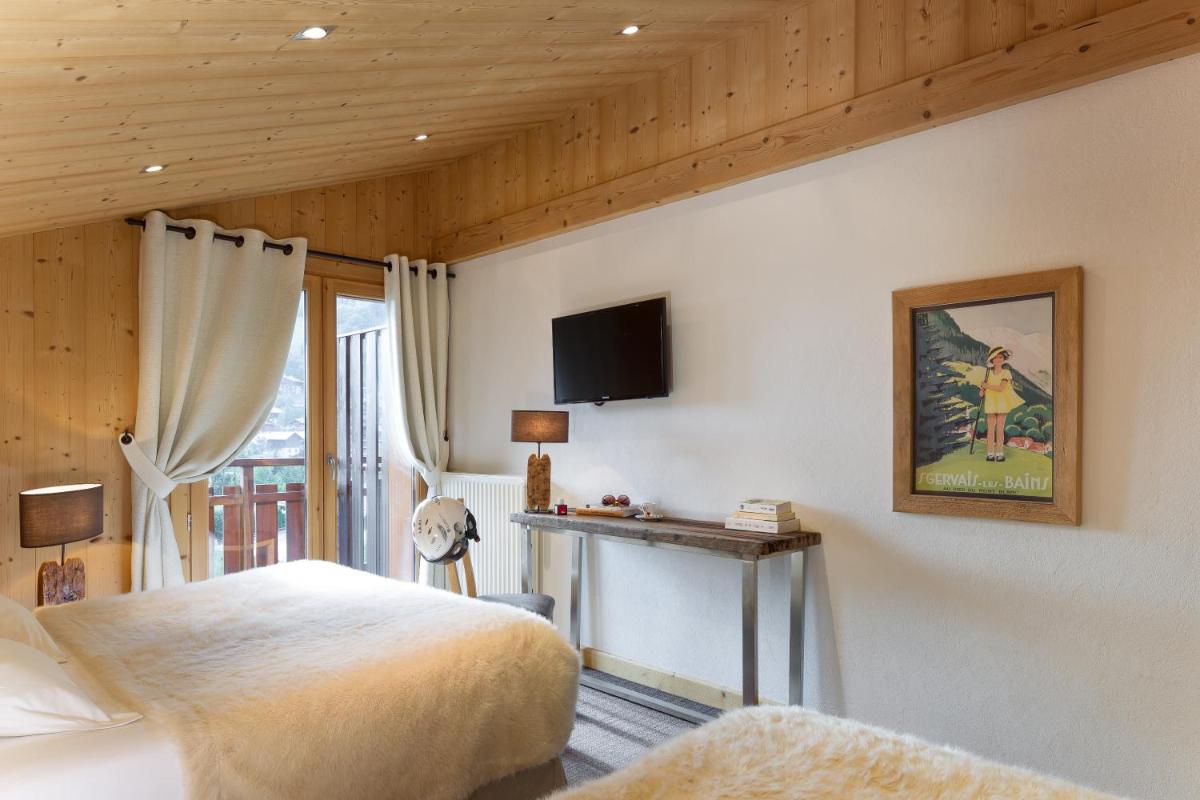 une chambre avec un lit et une télévision sur un mur dans l'établissement Hôtel et Spa Le Delta, au Grand-Bornand