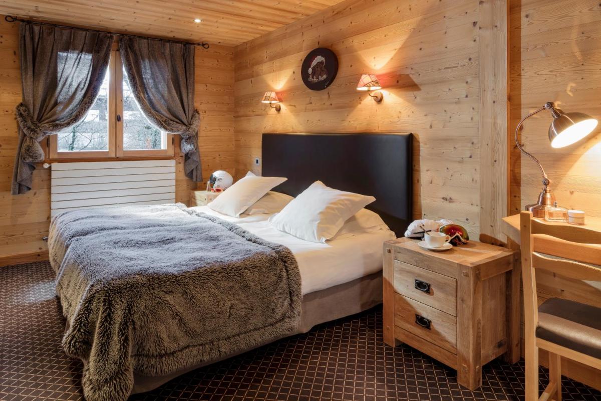 une chambre avec un lit et un mur en bois dans l'établissement Hôtel et Spa Le Delta, au Grand-Bornand