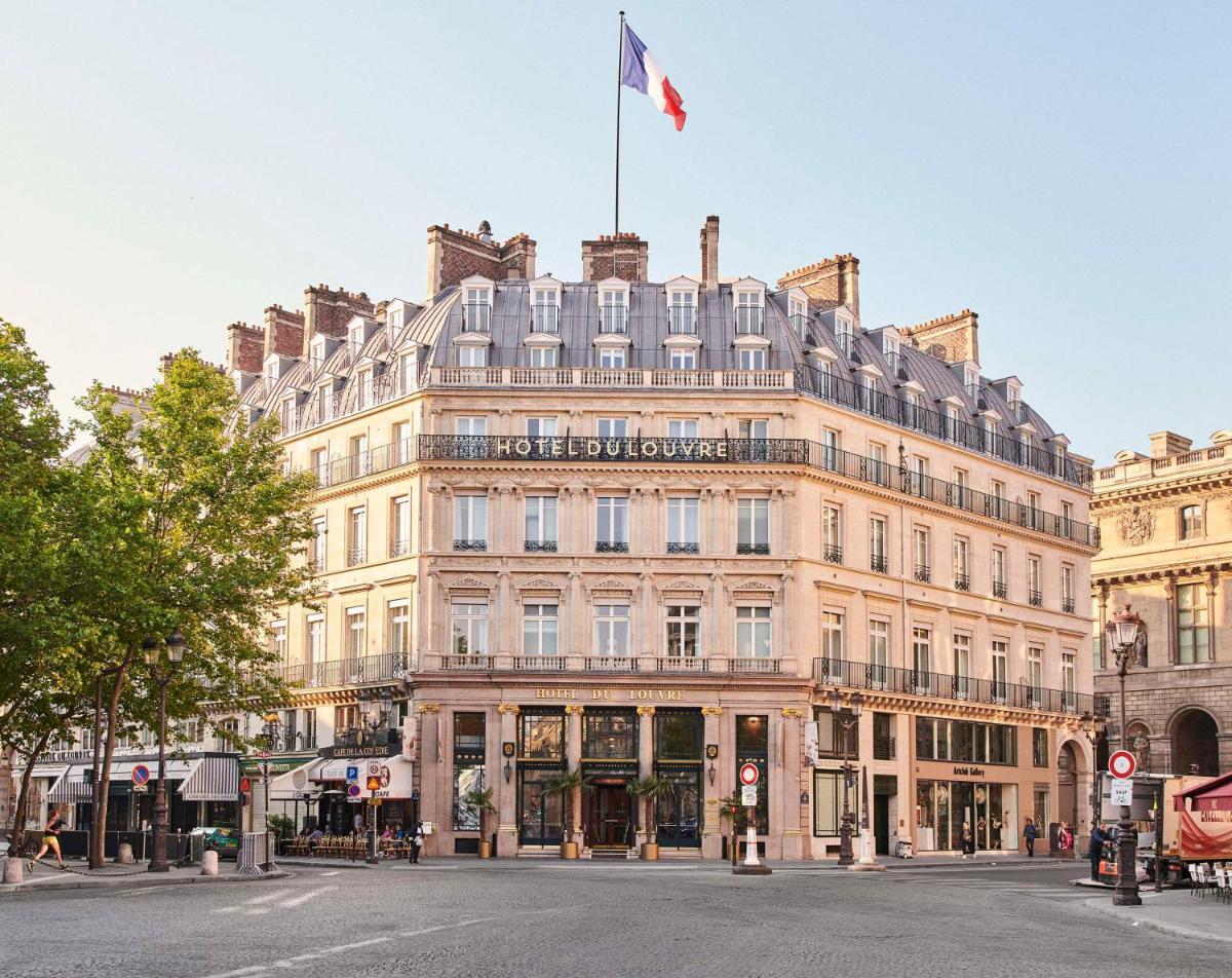 un grand bâtiment avec un drapeau en haut dans l'établissement Hôtel du Louvre, in The Unbound Collection by Hyatt, à Paris