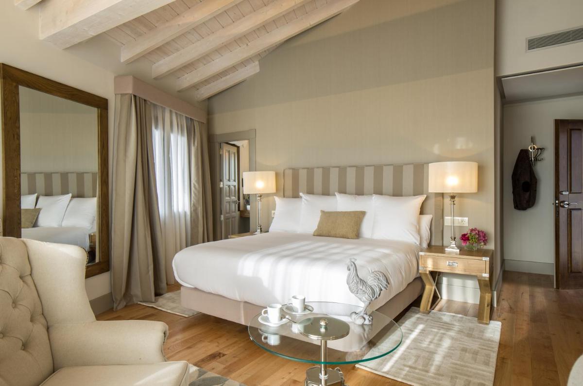 Un dormitorio con una gran cama blanca y un sofá. en Puebloastur Eco Resort Hotel & Spa, en Cofiño