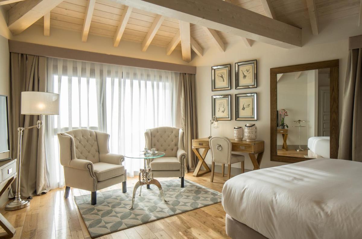 Un dormitorio con una cama y una mesa y sillas. en Puebloastur Eco Resort Hotel & Spa, en Cofiño 88 fotos más