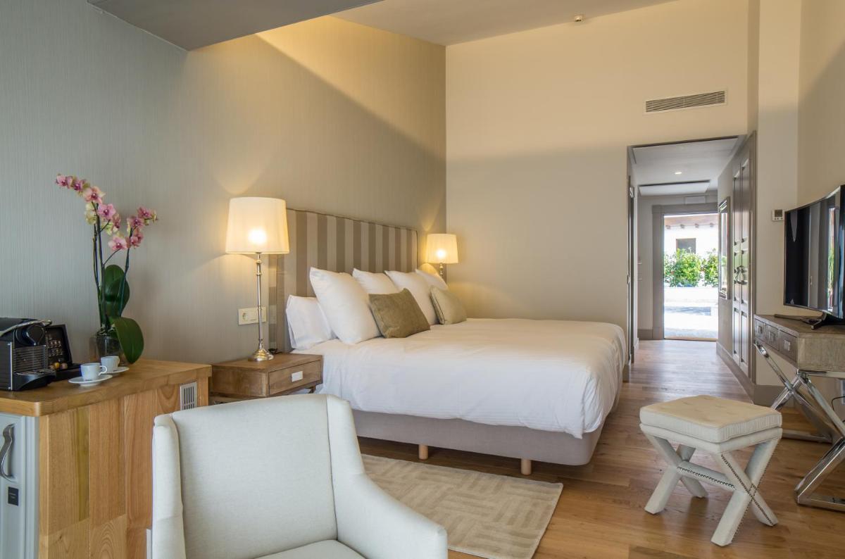 Un dormitorio con una cama y una silla y un televisor. en Puebloastur Eco Resort Hotel & Spa, en Cofiño