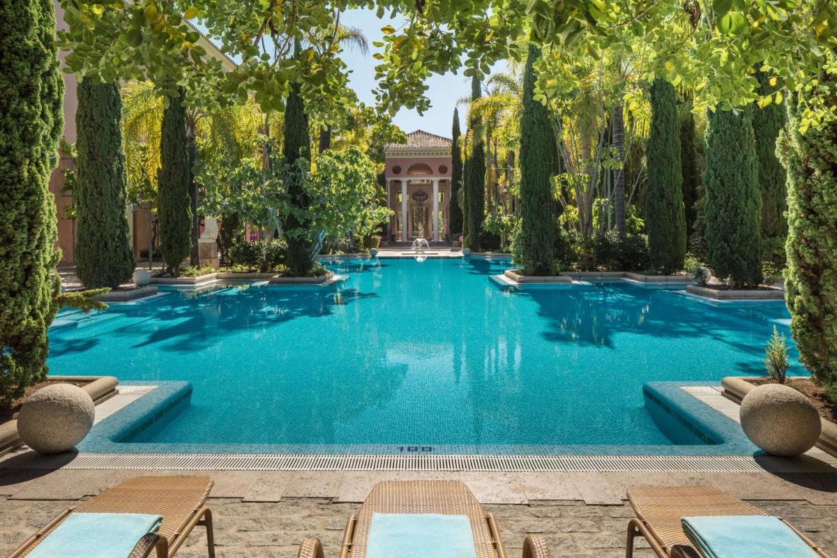 Una piscina con árboles y un edificio. en Anantara Villa Padierna Palace Benahavís Marbella Resort - A Leading Hotel of the World, en Estepona