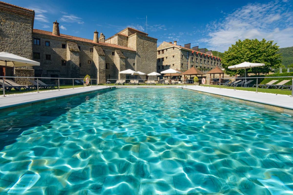 una piscina en un complejo con edificios en el fondo en Hotel & Spa Monasterio de Boltaña, en Boltaña