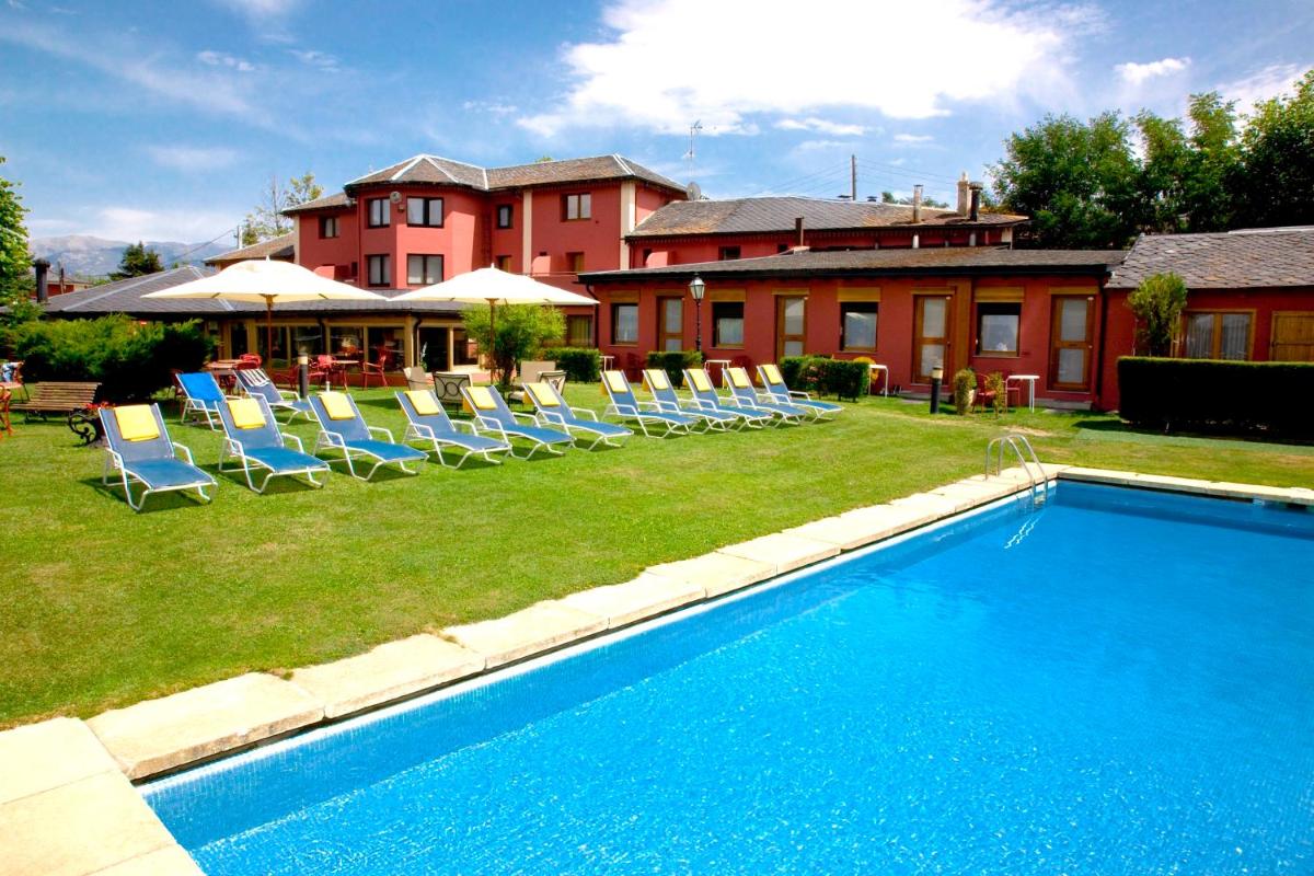 Una piscina con tumbonas y un edificio. en Hotel Del Lago, en Puigcerdà