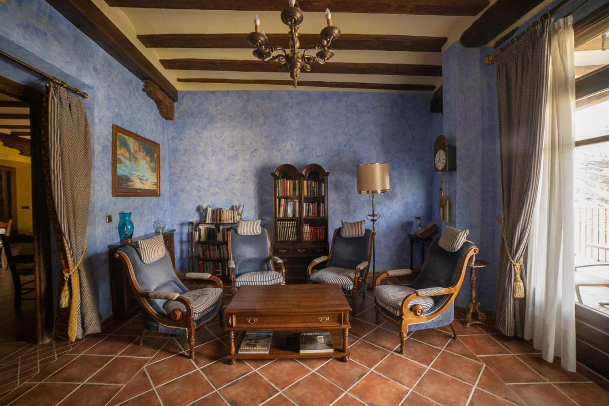 una sala de estar con paredes y sillas azules y una mesa. en Hotel SPA Don Iñigo de Aragón, en Las Cuevas de Cañart