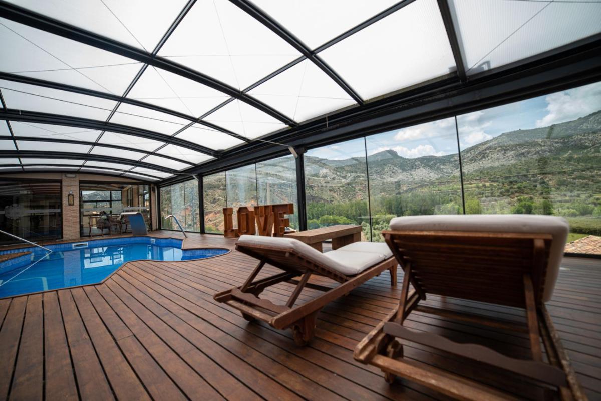 Habitación con terraza con sillas y piscina. en Hotel SPA Don Iñigo de Aragón, en Las Cuevas de Cañart