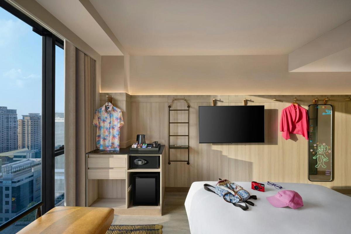 a hotel room with a bed and a flat screen tv at Moxy Mumbai Andheri West in Mumbai