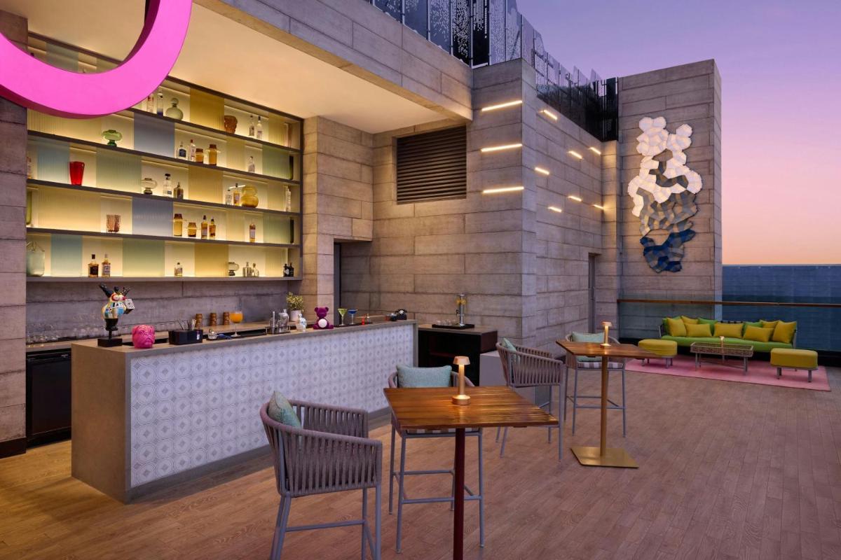 a restaurant with a bar with tables and chairs at Moxy Mumbai Andheri West in Mumbai